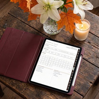 2026-2027 Weeklie month hub page on an iPad in a burgundy case beside lilies