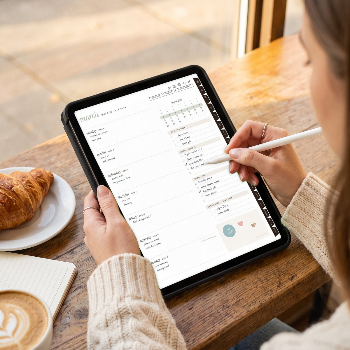 Writing on the student weekly spread on an iPad at a cafe table