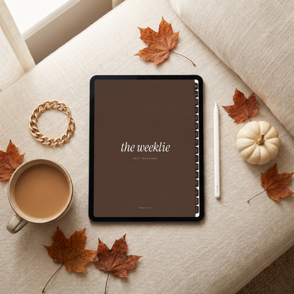 The 2027 Weeklie digital planner cocoa cover on an iPad in a fall flat lay with chai and maple leaves