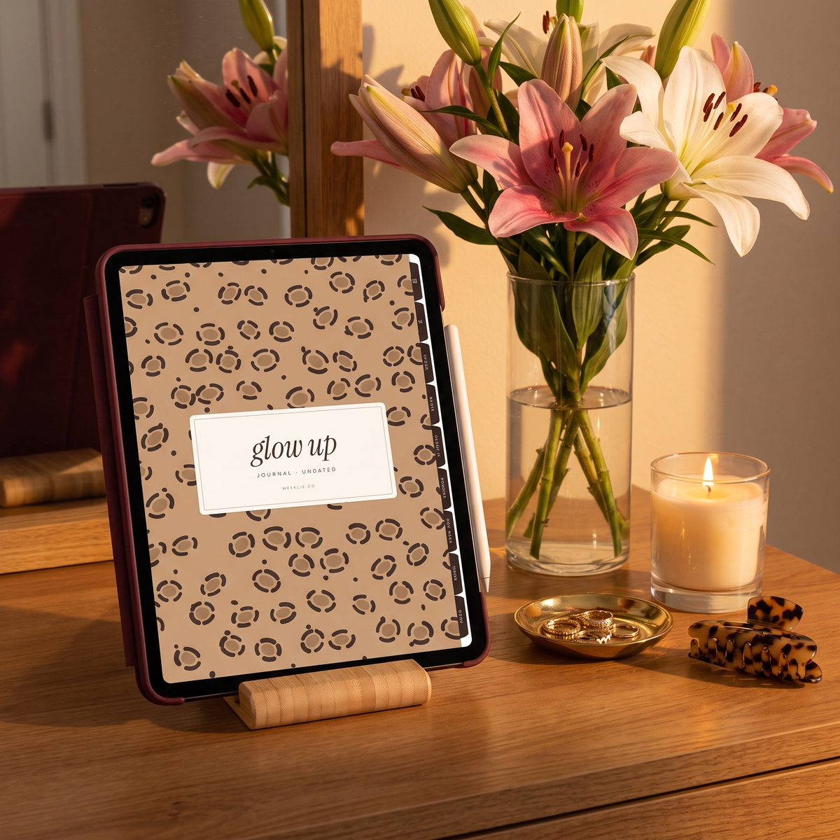 iPad in a burgundy case on a stand showing the Glow Up journal leopard cover with lilies