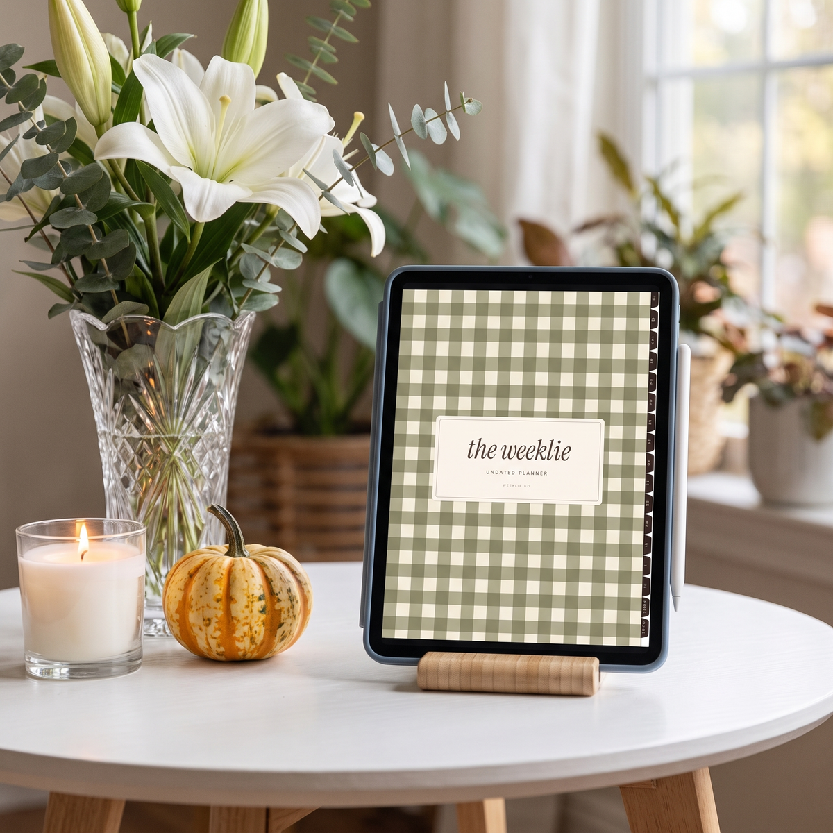 iPad on a wood stand showing the undated planner cover with lilies and a candle